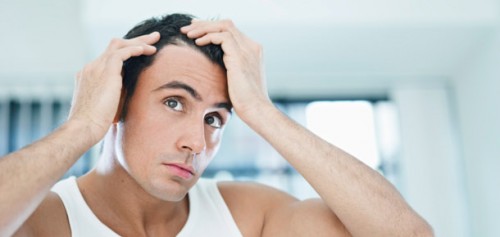 Stock image of a male model checking his hair loss with both hands