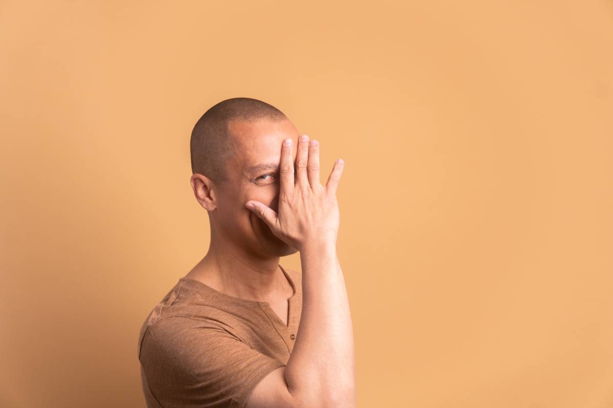 man hiding face with bald head