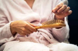 Close up photo of wooden hair brush and lost hairs.