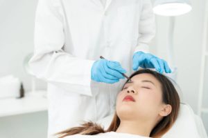 Surgeon preparing patient for eyebrow restoration procedure to create natural-looking eyebrows.